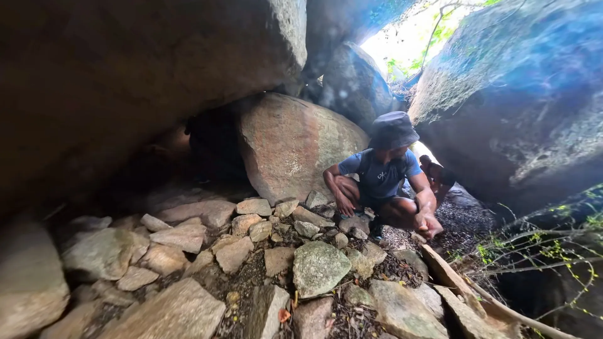 Squeezing into a cave entrance among the boulders